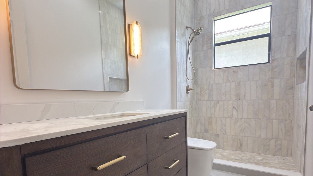 Dark wood vanity with brass hardware and brass-framed mirror