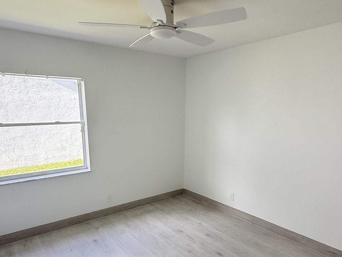 Bedroom with ceiling fan and new wood-look flooring, full home renovation