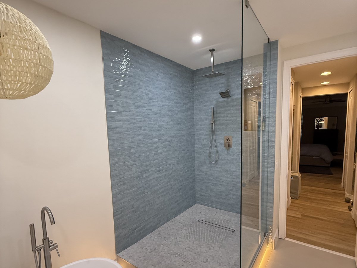 Coastal-style walk-in shower with blue glazed tile and freestanding tub