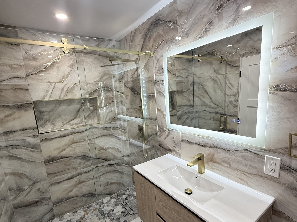 Book-matched marble bathroom with brass shower fixtures and floating vanity
